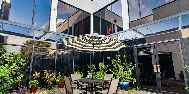 Outdoor patio with table, umbrella, and lush potted plants