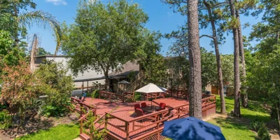 Outdoor deck by trees with seating.