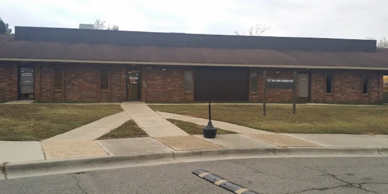 Exterior of facility with accessible pathways and signage on lawn post.