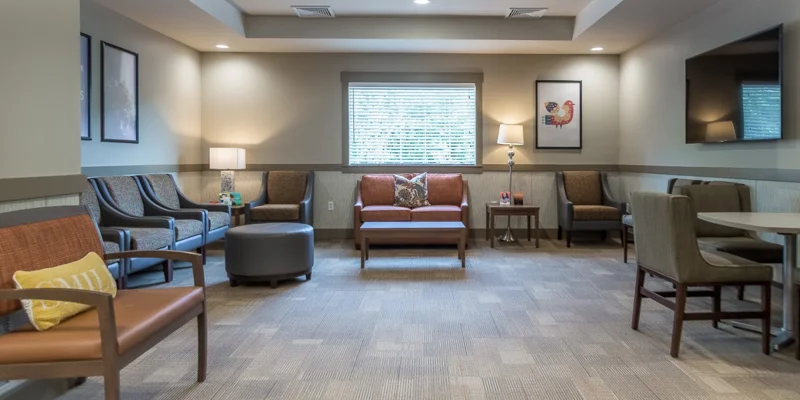 Spacious lounge with various seating, warm lighting, and a TV.