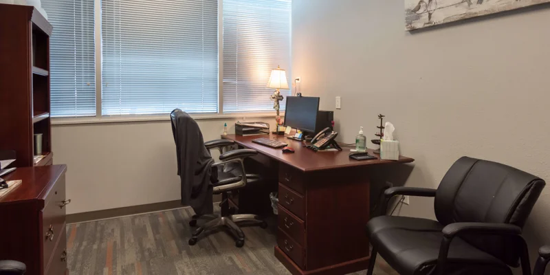 A professional office space with a desk, chair, and window blinds.
