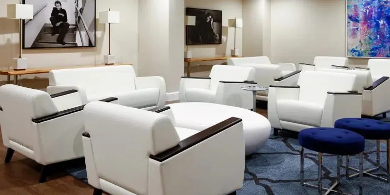 Lounge with white chairs, blue stools, and framed art.