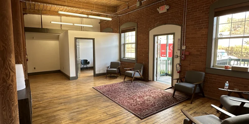 Waiting area with modern chairs, large windows, and hardwood floors