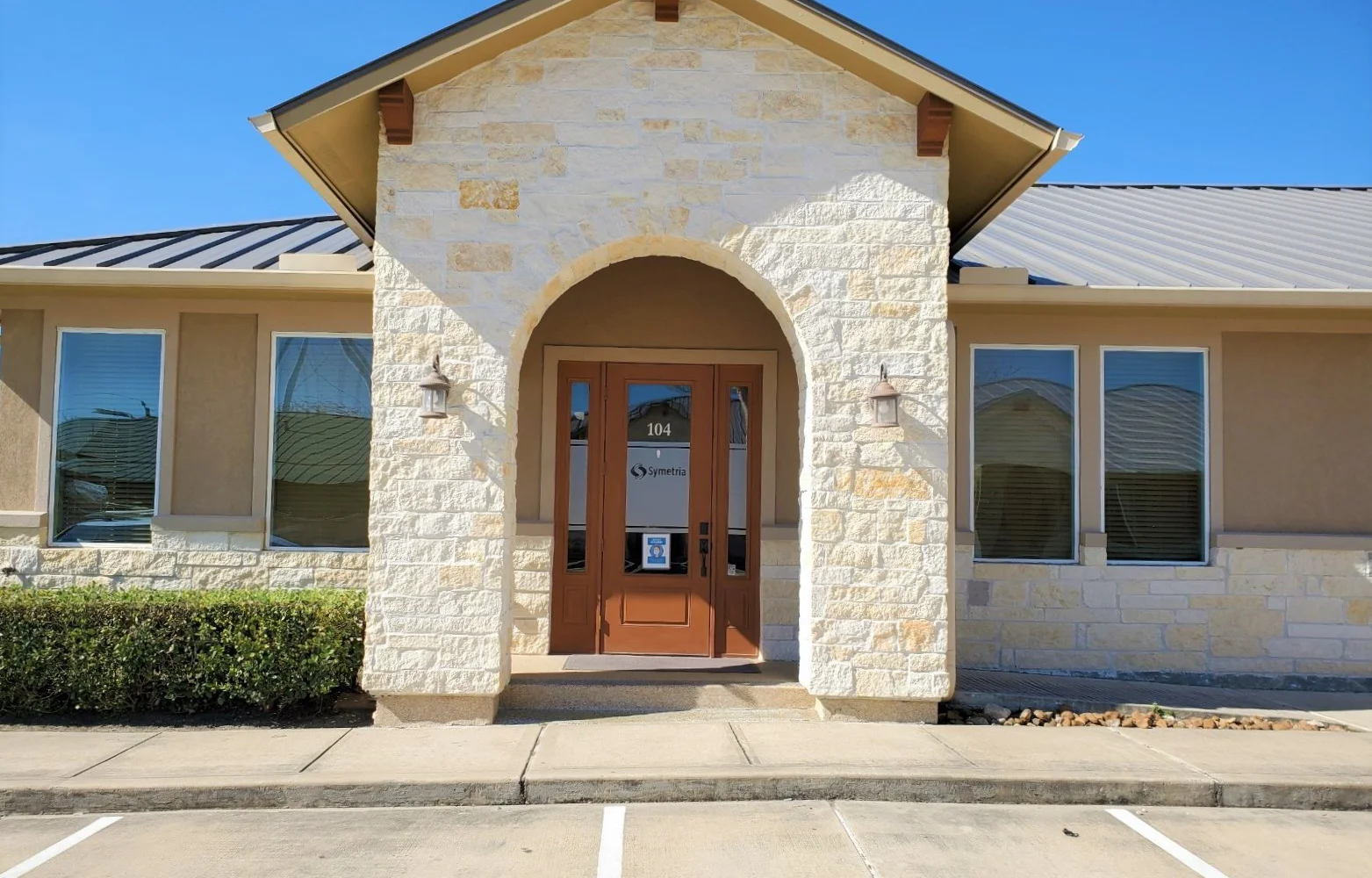 The exterior of Symetria Recovery with a stone entrance and glass doors.