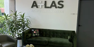 A reception area with a green couch, wooden tables, and a logo on the wall.
