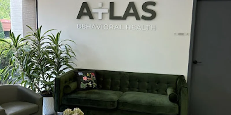 A reception area with a green couch, wooden tables, and a logo on the wall.