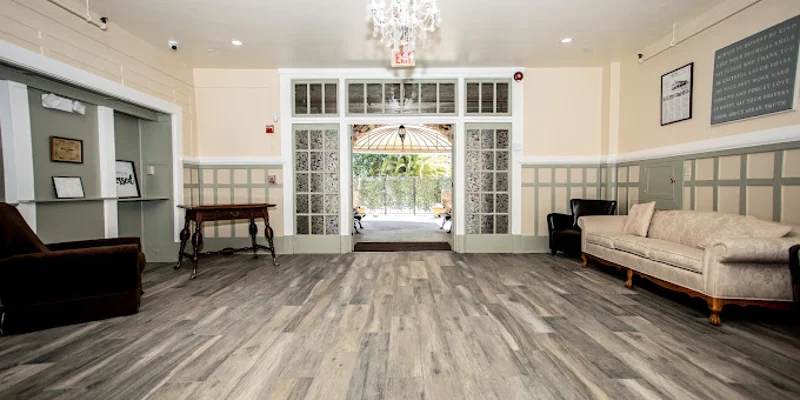 A spacious lounge with seating, wooden floors, and a chandelier.