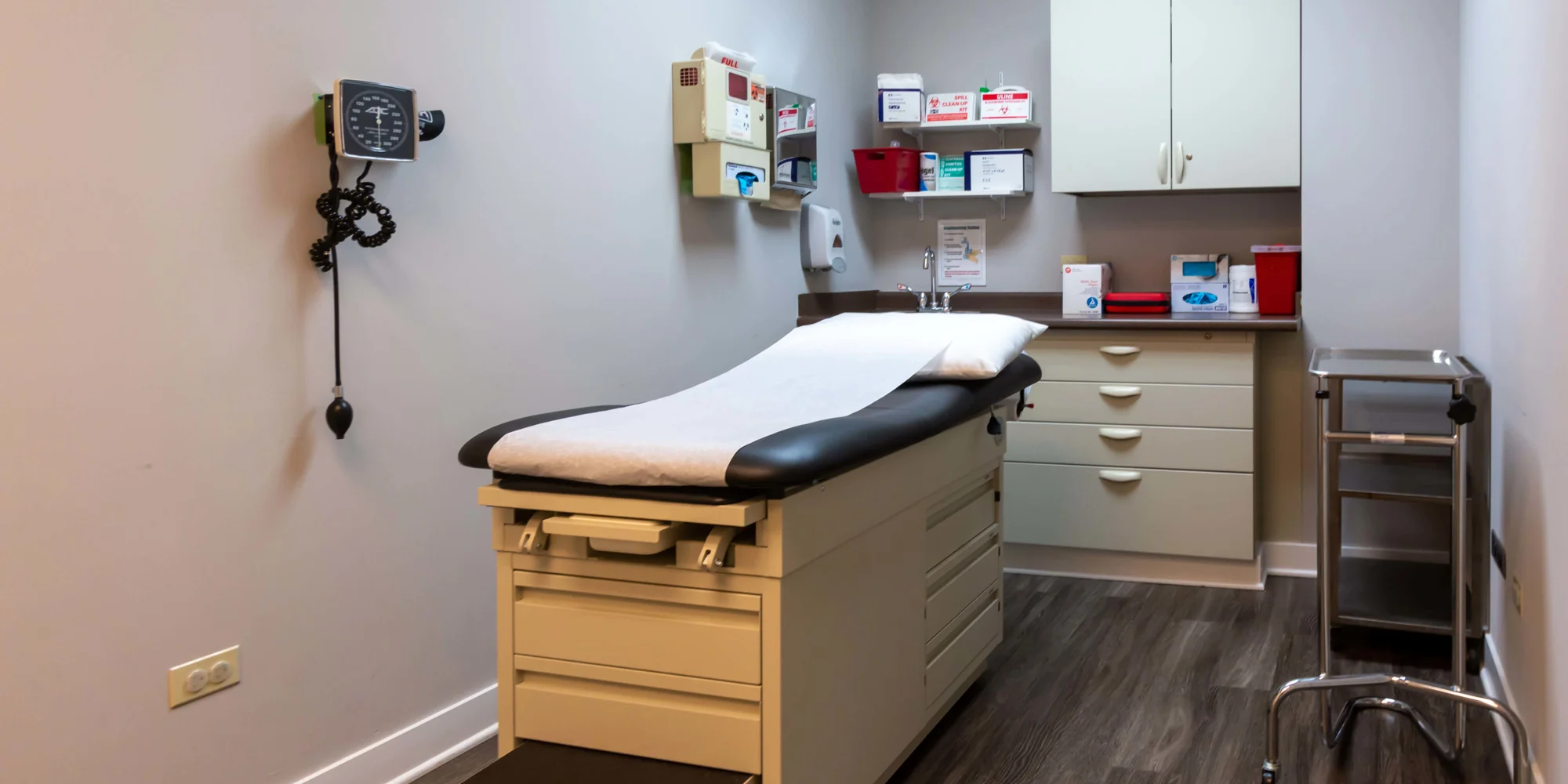 A medical exam room with a patient bed and cabinets.