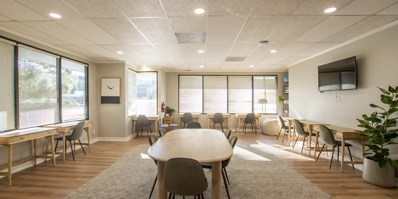 Spacious study area with multiple desks, chairs, and large windows