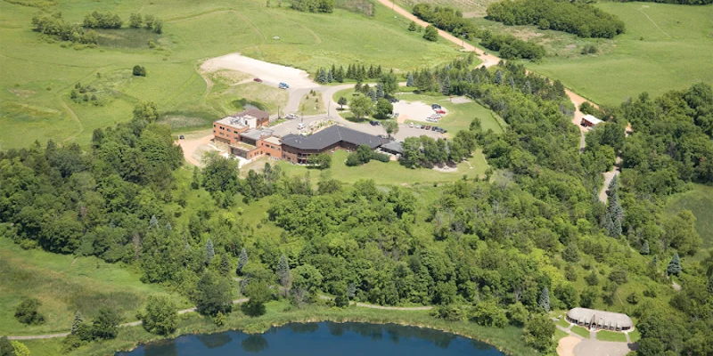 Aerial view of rehab facility surrounded by greenery next to a lake.