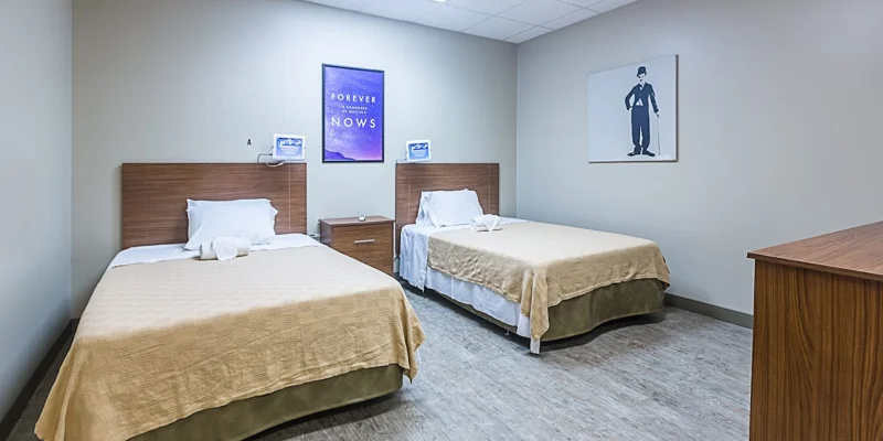 Bedroom with two twin beds, wooden headboards, and wall art.