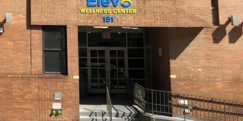 Red-brick exterior with big windows near entrance walkway.