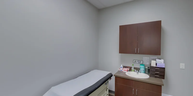 A small medical exam room with a patient bed and cabinets