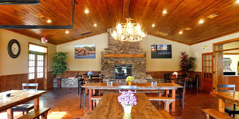 Rustic dining area with wooden tables and stone fireplace