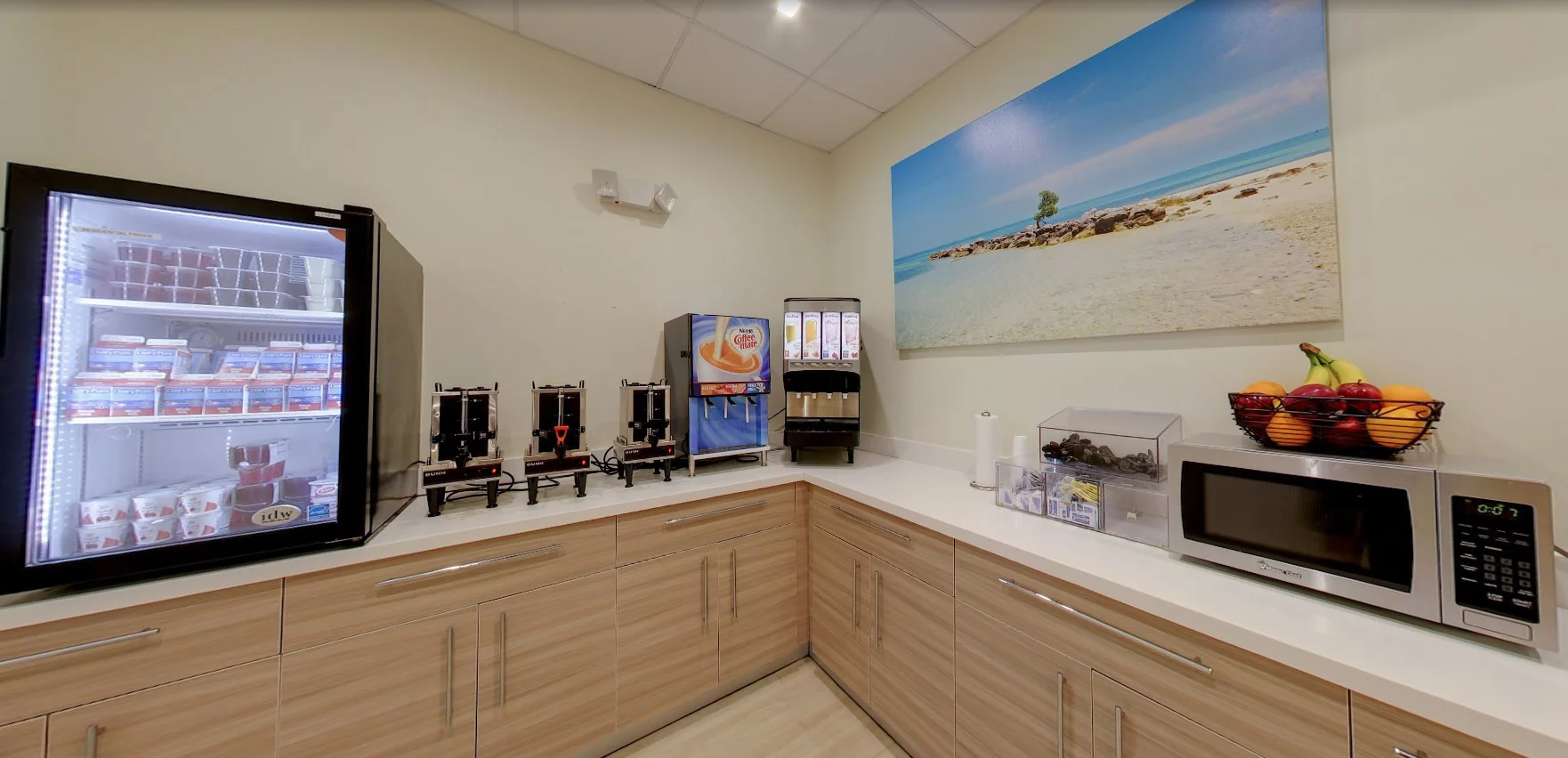 Kitchen with drink dispensers and a fridge.