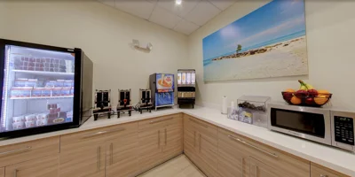 Kitchen with drink dispensers and a fridge.