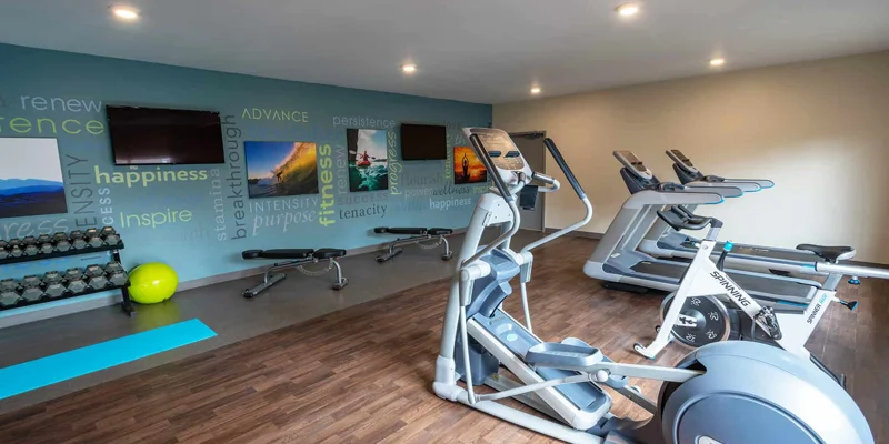 A modern gym with treadmills, weights, and motivational wall art.