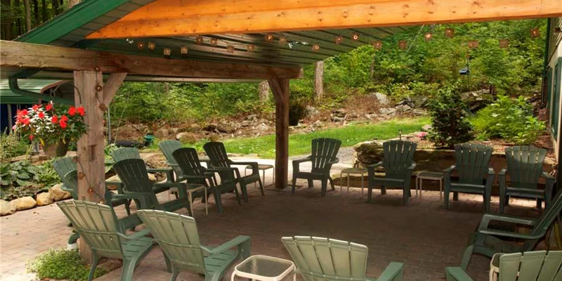 A tranquil covered patio with Adirondack chairs in a forest setting