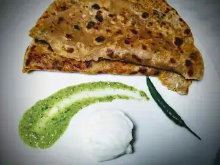 cauliflower stuffed flatbread serving with green chutney