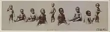 Nine dark-skinned African-American children, all naked, several with exposed male genitalia, all appearing to be toddlers between ages one and three, sit or stand in a variety of body positions; original caption reads Alligator bait with a copyright notice by McCrary & Branson of Knoxville, Tennessee dated 1897