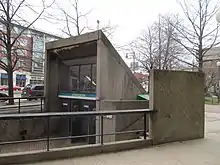 A glass and concrete subway entrance in an urban plaza