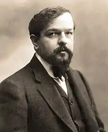 middle-aged white man with full head of dark hair and neat moustache and beard