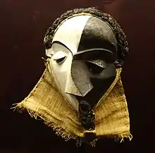 Mbangu mask; wood, pigment & fibres; height: 27&nbsp;cm; by Pende people; Royal Museum for Central Africa. Representing a disturbed man, the hooded V-looking eyes and the mask's artistic elements – face surfaces, distored features, and divided colour – evoke the experience of personal inner conflict