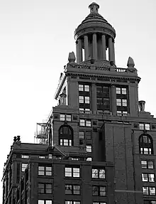 A high rise building with many tiers and a ten-columned cupola topping it.