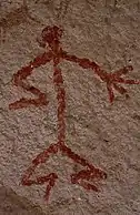 Humanoid stick figure painted on a rock wall in red. The figure is shown in Stylistic group&nbsp;C.