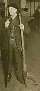 Man holding a crosscut saw and a peavey.