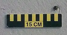 A ball of tar about 1&nbsp;cm (0&nbsp;in) wide on sand above a 15&nbsp;cm (6&nbsp;in) scale
