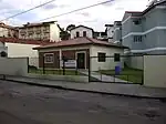 A small lot with a garden surrounded by walls and a gate with the Kingdom Hall in its center