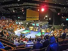 Interior of the Crucible Theatre with two snooker tables in the centre surrounded by seating