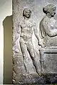 Relieve votivo en el banquete fúnebre. Joven esclavo desnudo sosteniendo un enócoe. Atenas, siglo&nbsp;V&nbsp;a.&nbsp;C.,  Museo Arqueológico Nacional de Atenas.
