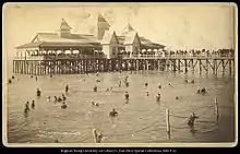 las personas nadando en el gran lago salado en utah en el verano; hay un edificio arriba del agua con muchas personas a dentro