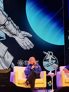 Fotografía de la Comandante Susan Kilrain en el campamento espacial Space 2101 en la Universidad de Ciencia y Tecnología Rey Abdalá en 2023. Hablando en un auditorio, sosteniendo un micrófono.