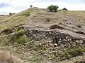 La muralla de la parte inferior del castro, donde se encontró una gran cantidad de puntas de flecha y de proyectiles metálicos pesados, de donde se deduce que esta fue la zona por donde se acometió el ataque más virulento a la muralla. Las hiladas detrás del derrumbe que están ordenadas, son las que delimitan el grosor de la muralla, alcanzando esta en torno a los 5&nbsp;m de ancho.