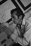Fundador del museo con un pututu y mapas al fondo.