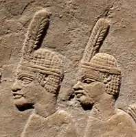 Prisioneros egipcios llevando el típico tocado de una pluma de los soldados de Taharqo.