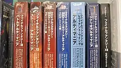 Seven thick large paperback books, each with different Japanese writing on the binding, wrapped in plastic, sitting on a shelf in a row