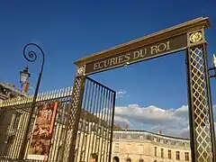 Detalle de la reja de acceso con el lema "Écuries du Roi" (Caballerizas del Rey).