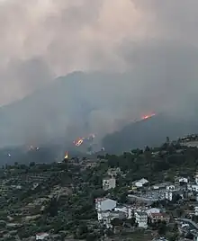 Incendio de Pedro Bernardo en 2022. Al fondo se encuentra el monte de la Abantera ardiendo y hay un humo negro y espeso. Delante se observan las últimas casas del pueblo