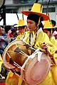 Músicos coreanos con vestidos  típicos, tocando el tambor janggu.