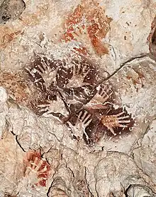 Le «&nbsp;Bouquet de mains&nbsp;», une manifestation remarquable de l’art rupestre de Bornéo, met en scène six mains dans une ronde graphique éternelle. A noter des mains de couleur rouge orangé plus anciennes recouvertes par le motif.