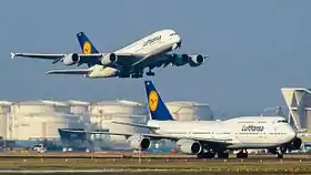 Lufthansa Airbus A380 aterrizando. En primer plano, Lufthansa Boeing 747-8, carreteando en la calle de rodaje.