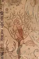 un buho bordado en rojo sobre fondo neutro con un ciervo, una tortuga...