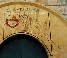 Reloj de sol situado en la portada de acceso de la plaza de la Iglesia