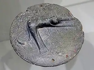 Tapa de pixis de pizarra verde con un perro representado, del 2500-2000&nbsp;a.&nbsp;C., Museo Arqueológico de Heraclión.