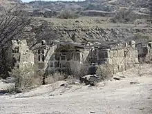 Breve Descripción: El Parque Provincial Ischigualasto es mundialmente famoso por su riqueza paleontológica. Sus sedimentos guardan las evidencias de todo el proceso evolutivo del triásico (Era Mezozóica). Además destacan una gran variedad de registros arqueológicos que hacen mención a la actividad humana que se desarrolló en tiempos remotos. En Ischigualasto, entre 1920 y 1954 se explotaron 3 minas de carbón. El carbón extraído era llevado a lomo de mula a las fraguas y los hornos de Huaco y Jáchal, a unos 70 km. Económicamente estas explotaciones eran muy pobres, por tratarse de mineral carbonoso de escasa pureza, razón por la cual fueron abandonadas. Los mineros que trabajaron estas minas, realizaron algunos conjuntos habitacionales muy rústicos utilizando material de la zona. Entre estas se encuentra la vivienda mostrada la cual fue construida con piedra, barro y ramas. Estas construcciones son de escasa altura y se ubican en una terraza reparada de los vientos entre el cauce de un río y cerros altos.