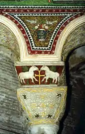 Decoración de mosaico y relieve policromado en los arcos y el capitel y cimacio de una columna en San Vital de Rávena, arte bizantino del siglo&nbsp;VI.